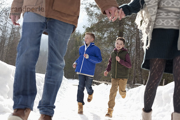 Jungen  die hinter den Eltern herlaufen und im Schnee Händchen halten.