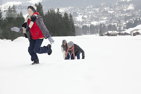 Mutter und Söhne spielen im Schneefeld
