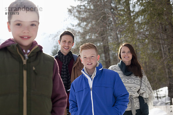 Porträt einer lächelnden Familie in verschneiten Wäldern