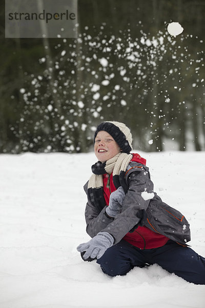 Porträt eines glücklichen Jungen  der die Schneeballschlacht genießt.