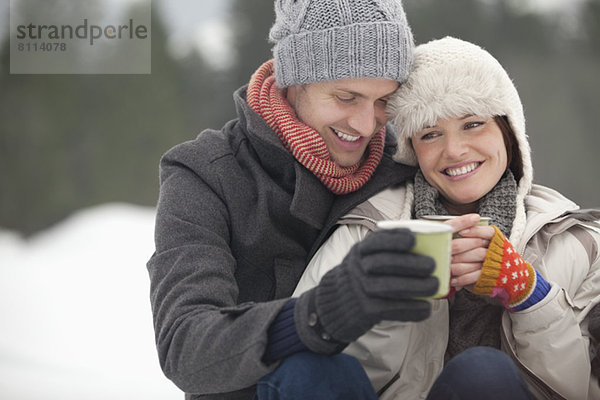 Glückliches Paar trinkt Kaffee im Schnee