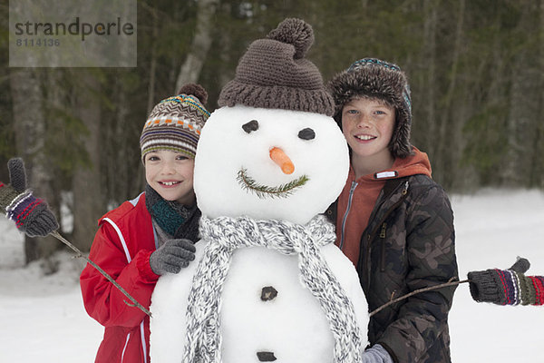 Porträt von glücklichen Jungen  die mit Schneemann posieren