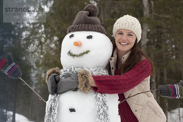 Porträt einer lächelnden Frau  die den Schneemann umarmt
