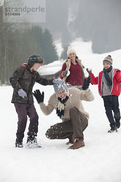 Glückliche Familie genießt Schneeballschlacht im Feld