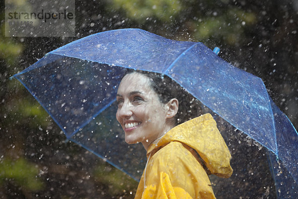 Glückliche Frau mit Schirm im Regen