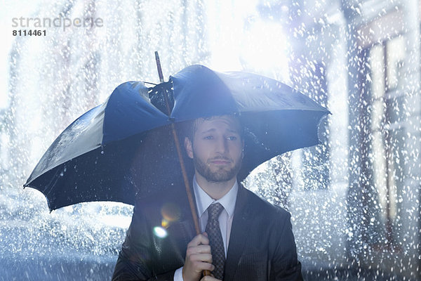 Frustrierter Geschäftsmann mit kaputtem Regenschirm
