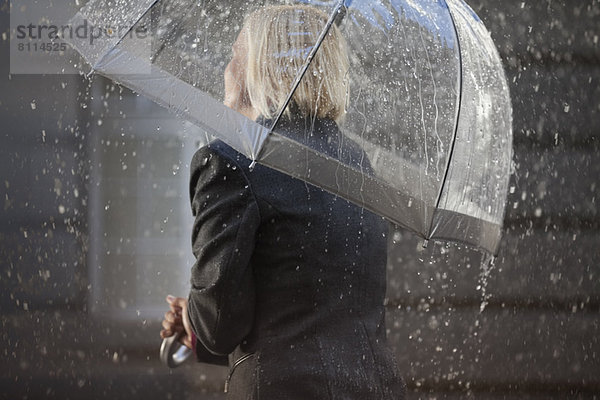Geschäftsfrau unter Schirm im Regen