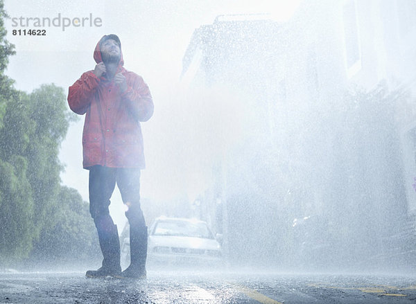 Mann im Regenmantel in verregneter Straße