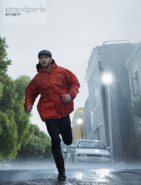 Mann im Regenmantel läuft im Regen