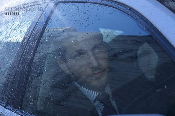 Nahaufnahme eines Geschäftsmannes im Auto mit Blick auf den Regen