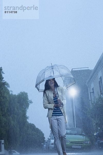 Fröhliche Frau mit Regenschirm  die im Regen läuft