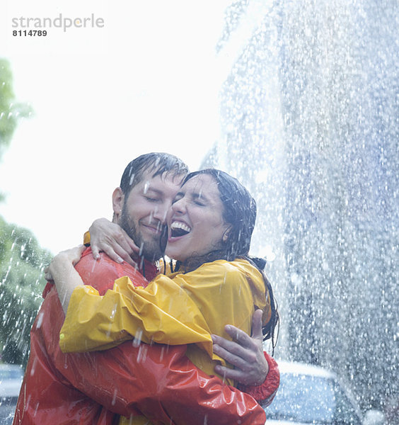 Glückliches Paar  das sich im Regen umarmt.