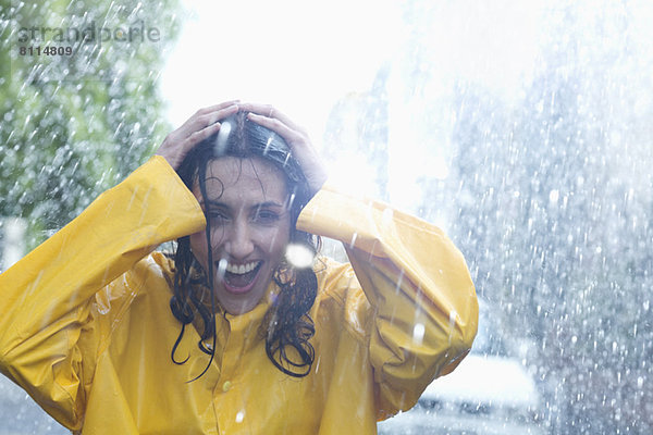 Glückliche Frau mit Händen auf dem Kopf im Regen