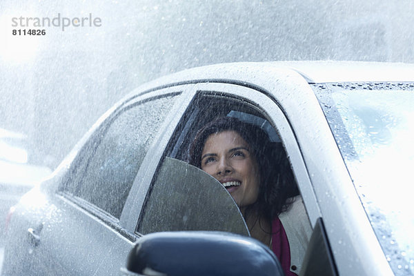 Lächelnde Geschäftsfrau im Auto mit Blick auf den Regen