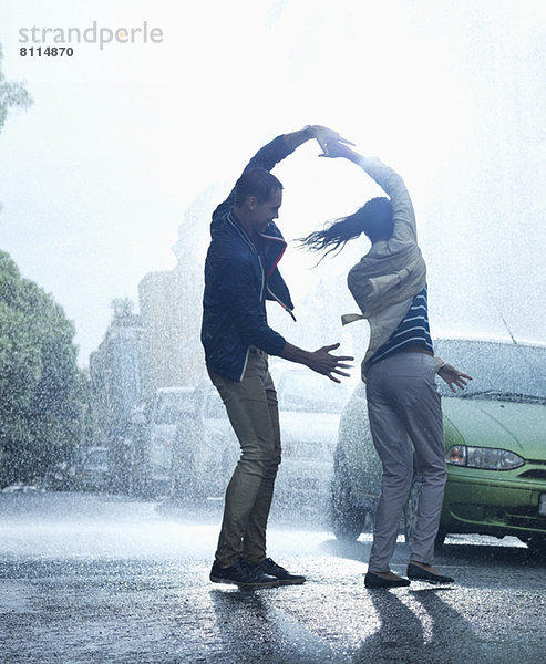 Glückliches Paar tanzt im Regen