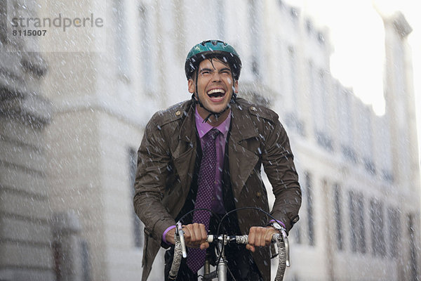Enthusiastischer Geschäftsmann beim Radfahren im Regen
