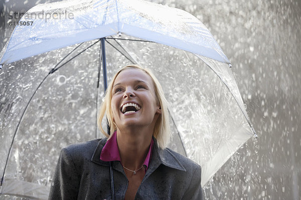 Lachende Geschäftsfrau unter dem Regenschirm