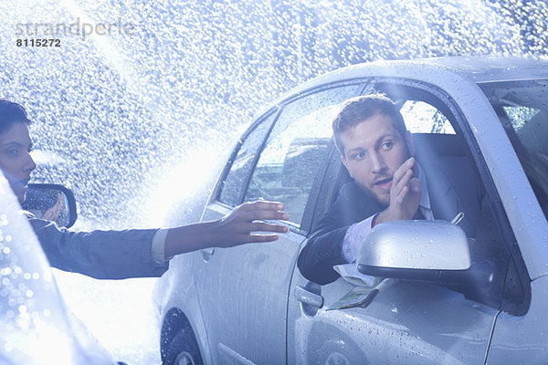 Geschäftsmann im Auto mit Wegbeschreibung für die Frau im Regen