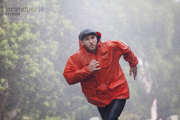 Mann im Regenmantel läuft im Regen