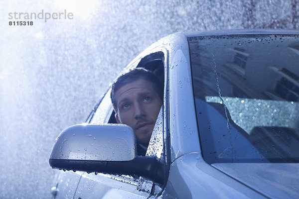 Geschäftsmann im Auto mit Blick aus dem Fenster auf Regen