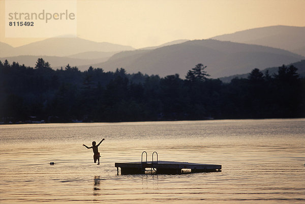 Vereinigte Staaten von Amerika USA Außenaufnahme Wasser Berg Farbaufnahme Farbe Begeisterung Ruhe Abenteuer Kindheit Abend Baum Mut Spiegelung See Natur Querformat springen Dock Fotografie Seitenansicht Holz Junge - Person freie Natur