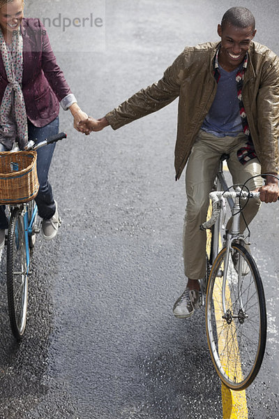 Glückliches Paar  das Händchen hält und Fahrräder fährt.