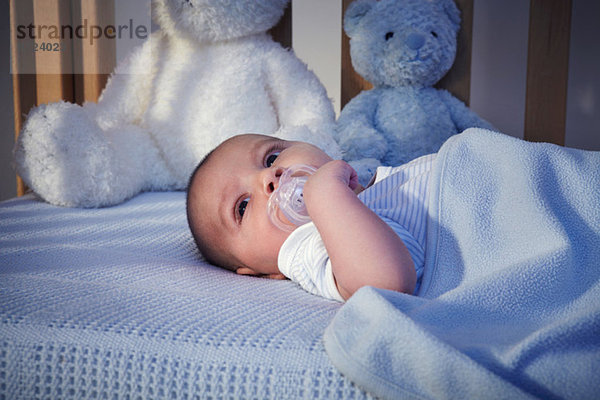 Babyboy und Teddybären in der Krippe bei Nacht