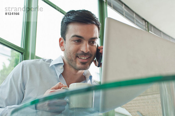 Junge männliche Büroangestellte im Gespräch mit dem Handy