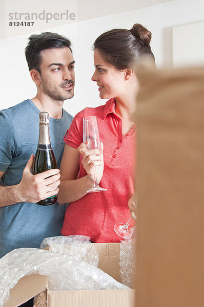 Junges Paar feiert mit Champagner unter Pappkartons