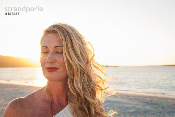 Blonde Frau mit geschlossenen Augen am Strand bei Dämmerung  Kapstadt  Südafrika