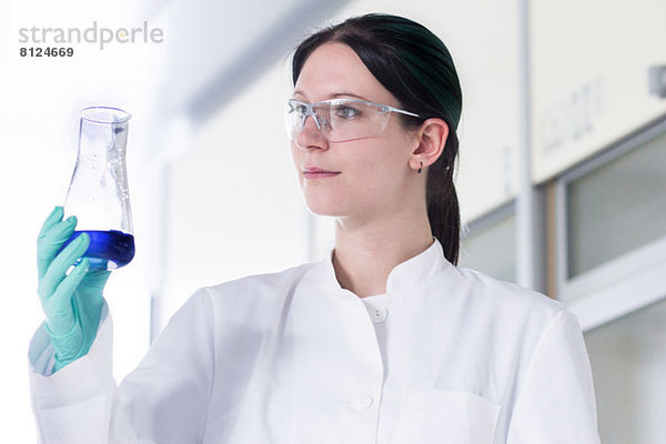 Portrait einer Wissenschaftlerin bei der Untersuchung von Glasbehältern