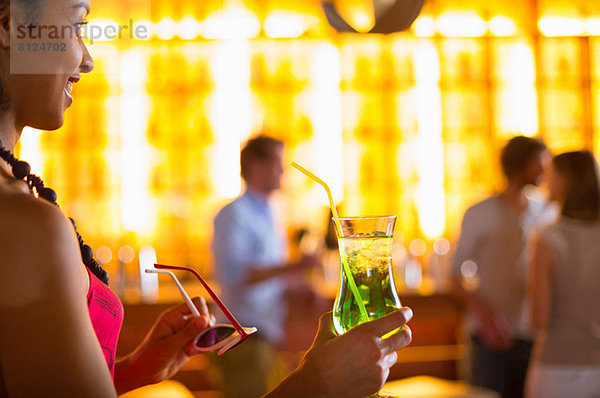 Junge Frau mit Cocktail und Sonnenbrille im Club