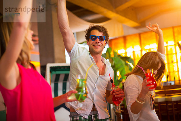 Gruppe von Freunden tanzt mit Cocktails in der Bar