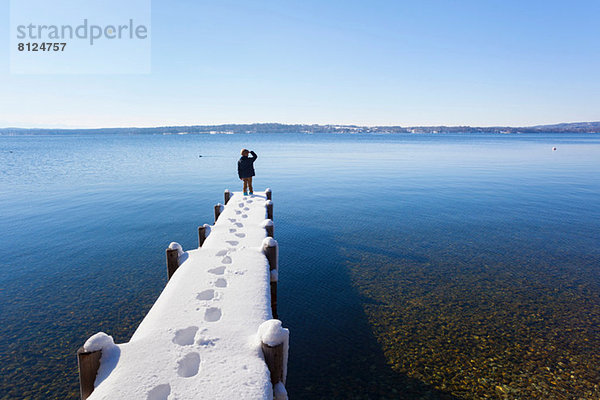 Junge auf schneebedecktem Pier  Starnberger See  Bayern  Deutschland