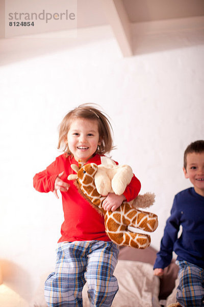 Zwei kleine Kinder beim Springen auf dem Bett