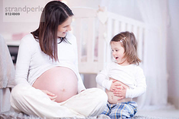 Schwangere Mutter und junge Tochter beim Vergleich von Unebenheiten