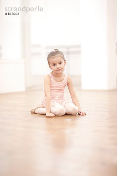 Porträt der jungen Ballerina auf dem Boden sitzend