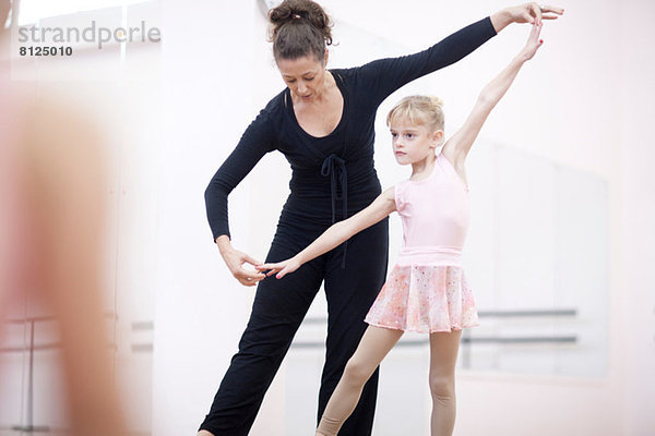 Junge Ballerina übt Pose mit Lehrerin