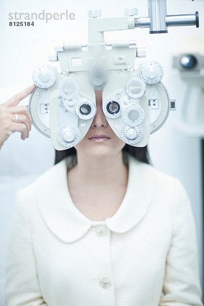 Junge Frau mit Sehtest beim Optiker