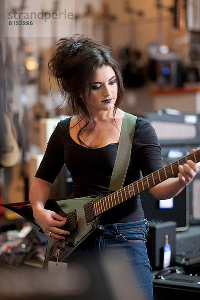 Junge Frau versucht E-Gitarre im Musikladen