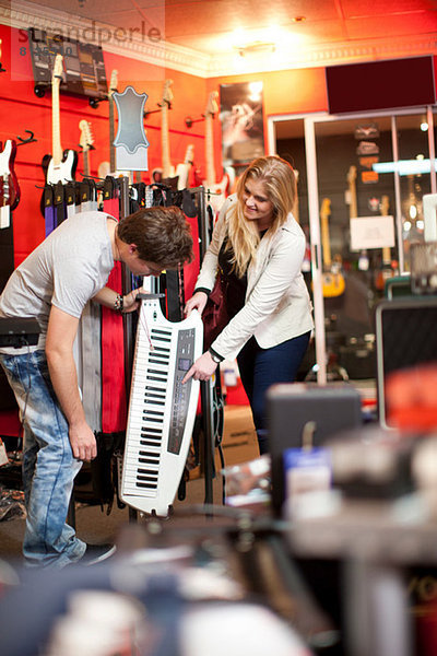 Junges Paar sucht Keytar im Musikladen