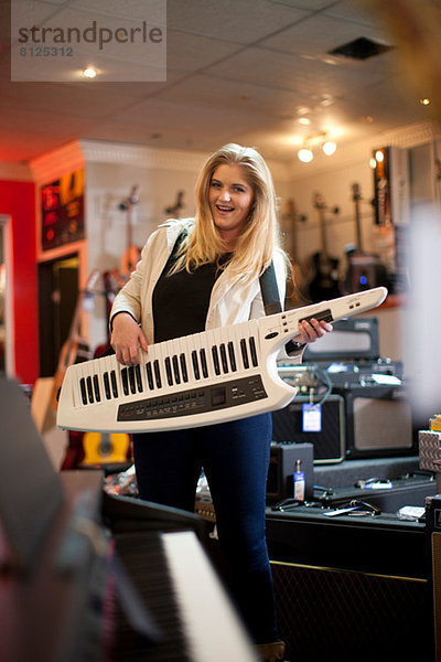 Junge Frau spielt Keytar im Musikladen