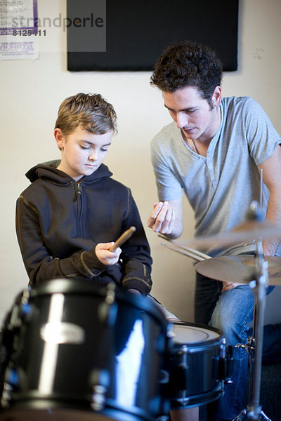 Junger Mann  der dem Jungen beibringt  wie man Drumsticks hält.