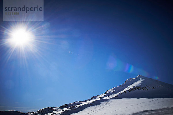 Sonnenbeschienener  schneebedeckter Berg in Österreich