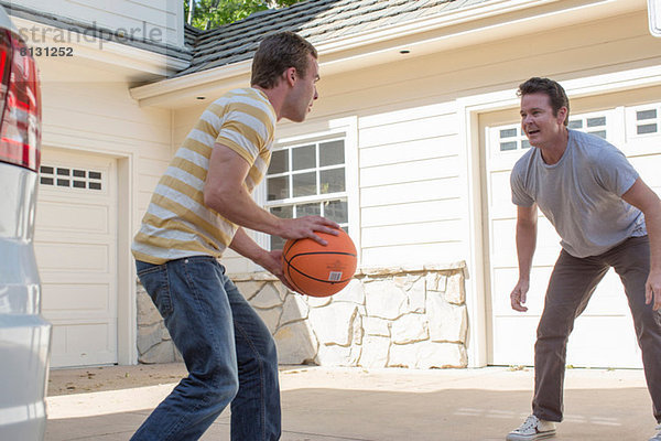 Vater und erwachsener Sohn spielen Basketball