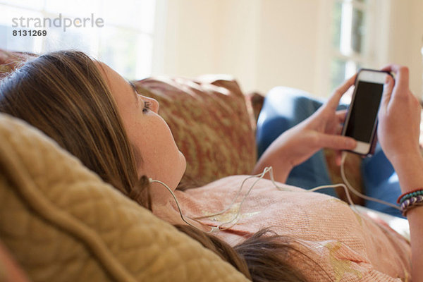 Teenagermädchen auf dem Sofa liegend mit Kopfhörer