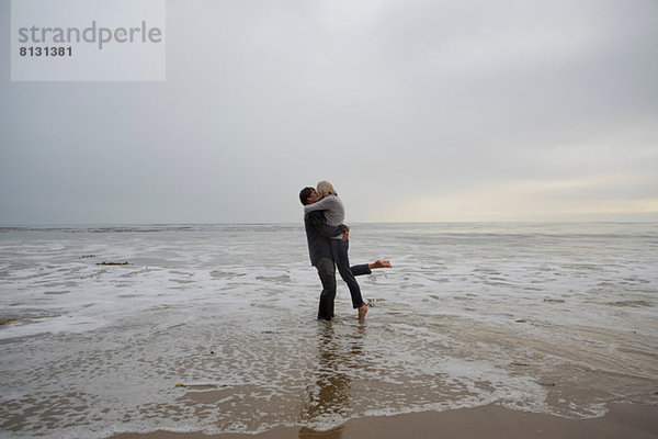 Ein reifes Paar  das sich am Strand umarmt.