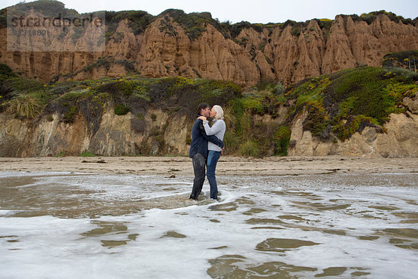 Ein reifes Paar  das im Meer steht und sich küsst.