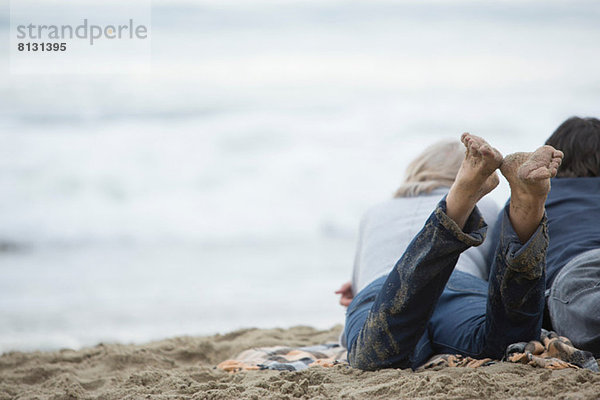 Ein reifes Paar  das am Strand liegt und aufs Meer schaut.
