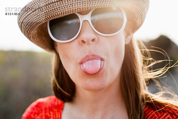 Reife Frau mit Sonnenbrille und herausstehender Zunge